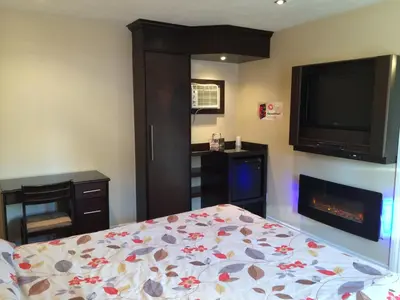 a bedroom with a bed and a flat screen tv at Olux Hotel-Motel-Suites in Laval