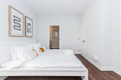 a white bedroom with a large white bed at Vast and perfectly located 3 bedroom flat by DenStays in Montréal