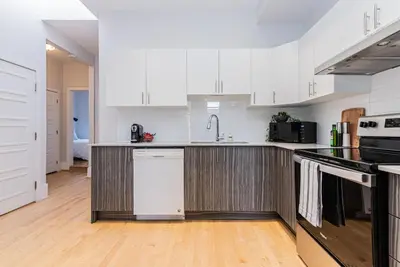 a kitchen with white cabinets and black appliances at New classy 2 bedroom apartment in Le Plateau by DenStays in Montréal
