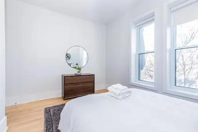 a white bedroom with a bed and a mirror at New classy 2 bedroom apartment in Le Plateau by DenStays in Montréal