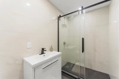 a white bathroom with a sink and a shower at Stonewall Suites in Montréal