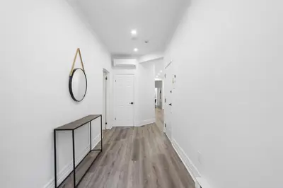 a hallway with white walls and wood floors and a mirror at Stonewall Suites in Montréal