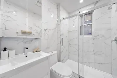 a white bathroom with a sink and a shower at Stonewall Suites in Montréal
