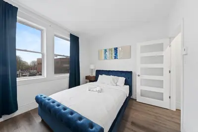a bedroom with a blue bed and a window at Stonewall Suites in Montréal