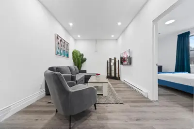 a living room with two chairs and a bed at Stonewall Suites in Montréal