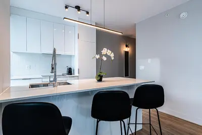 a kitchen with white cabinets and black chairs at WERFY Luxury Apart-Hotel in Montréal