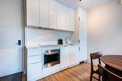 a kitchen with white cabinets and a wooden table at WERFY Luxury Apart-Hotel in Montréal