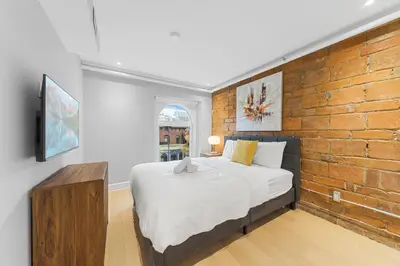 a bedroom with a bed and a brick wall at Suites De la Montagne in Montréal