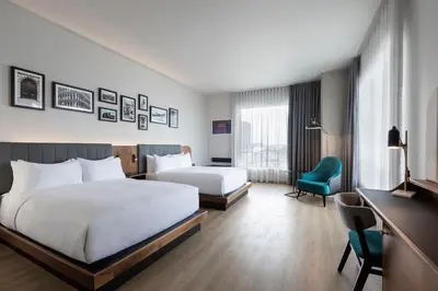a hotel room with two beds and a green chair at Hyatt Centric Montreal in Montréal