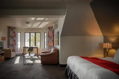 a bedroom with a bed and a chair and a desk at L'Auberge Du Lac St-Pierre in Trois-Rivières