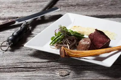 a plate of food with meat and vegetables on a table at L'Auberge Du Lac St-Pierre in Trois-Rivières