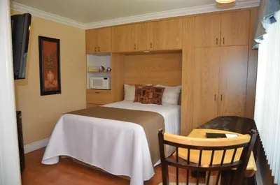 a small bedroom with a bed and a chair at Motel Derfal in Repentigny