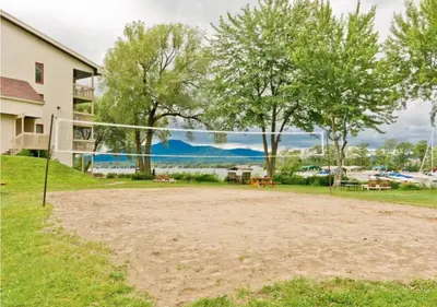 a volleyball court in front of a house with trees at Magog Waterfront Condo in Magog-Orford