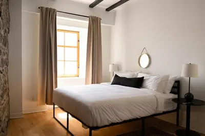 a bedroom with a bed with white sheets and a window at Maison Rasco by Luxury In Transit in Montréal