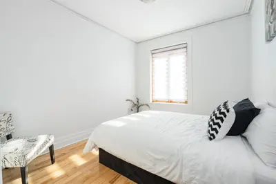 a white bedroom with a bed and a chair at Centennial 6-Bedroom Waterfront Palace Sleeps 14 in Montréal