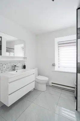 a white bathroom with a toilet and a sink at Centennial 6-Bedroom Waterfront Palace Sleeps 14 in Montréal