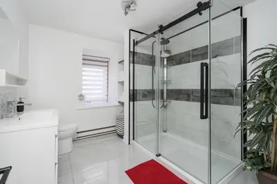 a bathroom with a glass shower with a red rug at Centennial 6-Bedroom Waterfront Palace Sleeps 14 in Montréal