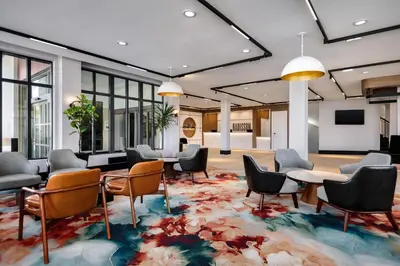 a lobby with chairs and tables on a rug at Radisson Hotel Montreal Airport in Saint-Laurent
