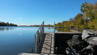 a wooden bridge over a large lake with rocks at Nice River & Mountain View+4 Beds+Free parking in McMasterville