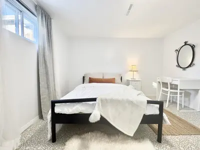 a white bedroom with a bed and a table at Montreal - Laval Haven - Entire Rental Unit in Laval