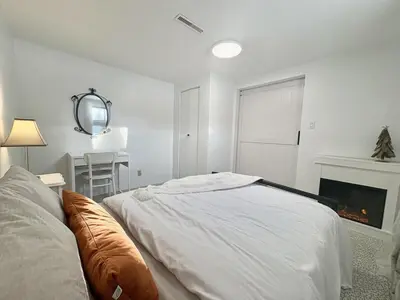 a white bedroom with a bed and a fireplace at Montreal - Laval Haven - Entire Rental Unit in Laval