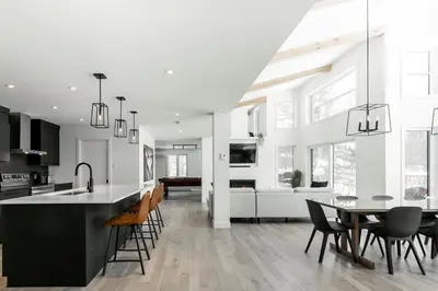 a kitchen and living room with a table and chairs at Chalet à léo - Spacieuse propriété haut de gamme avec vue sur Jay Peak in Mansonville