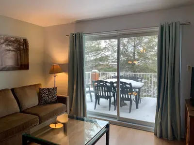 a living room with a couch and a sliding glass door at Condo Club Azur Plage Memphremagog in Magog-Orford