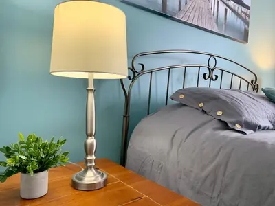 a lamp on a wooden table next to a bed at Condo Club Azur Plage Memphremagog in Magog-Orford
