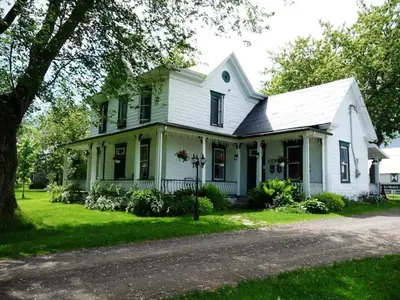 a white house with a tree and a driveway at La Maison des Leclerc in Trois-Rivières