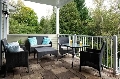 a patio with chairs and a table on a porch at Le Champlain 101- Condo avec Piscine in Bromont