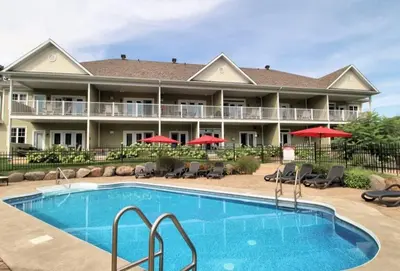 a pool in front of a hotel with red umbrellas at Le Champlain 101- Condo avec Piscine in Bromont