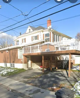 a large house with a large deck in front of it at Le Vétérans , Au Cœur du Centre-Ville , Tout à Pied ! in Lac-Mégantic
