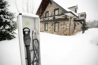 a parking meter in the snow in front of a house at Condo Hotel Au pied du Mont Orford in Orford