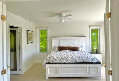 a bedroom with a bed and two windows at Newly Renovated villa with magnificent views in Coaticook