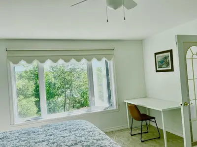 a bedroom with a bed and a desk and a window at Newly Renovated villa with magnificent views in Coaticook