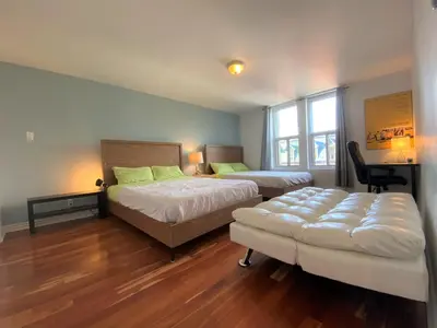 a bedroom with two beds and a chair and a desk at ReUnion in Montréal
