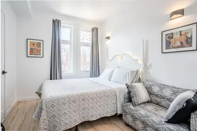 a white bedroom with a bed and a couch at hotel le coach in Montréal