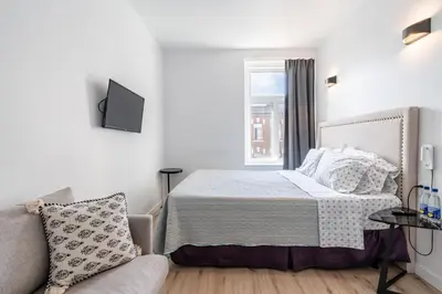 a bedroom with a bed and a couch and a window at hotel le coach in Montréal