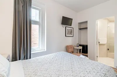 a white bedroom with a bed and a window at hotel le coach in Montréal