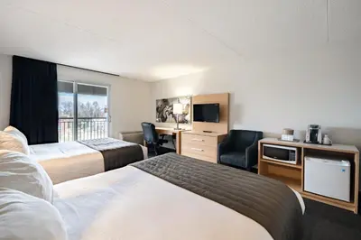 a hotel room with two beds and a desk at Hotel de la Rive in Sorel