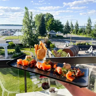 a person holding a tray of food on a balcony at Hotel de la Rive in Sorel