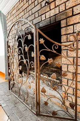 a fireplace with a metal gate next to a brick wall at Chez l'Doc in Saint-Prosper