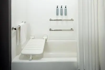 a white bathroom with a bench in a tub at Courtyard Montreal Midtown in Montréal