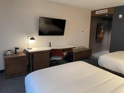 a hotel room with two beds and a desk and a tv at Courtyard Montreal Midtown in Montréal