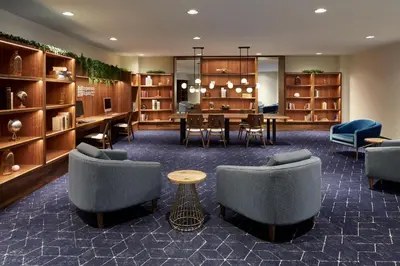 a waiting area with chairs and a table and a dining room at Courtyard Montreal Midtown in Montréal