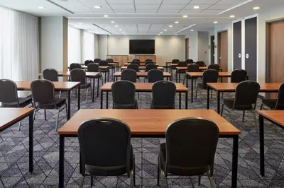 an empty room with tables and chairs and a projection screen at Courtyard Montreal Midtown in Montréal