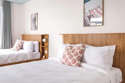 two beds in a hotel room with white and pink pillows at Hôtel le Rosay in Venise-en-Québec