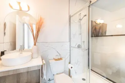 a white bathroom with a sink and a shower at Hôtel le Rosay in Venise-en-Québec