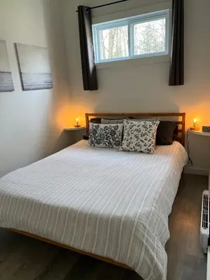 a bedroom with a large bed with two pillows at Capsule de Bonheur in Bromont