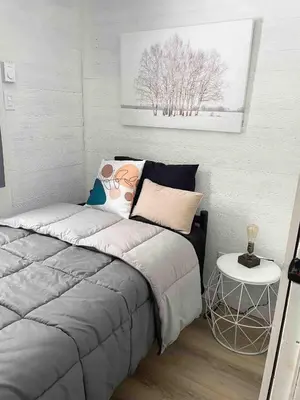 a small bedroom with a bed and a table at Capsule de Bonheur in Bromont
